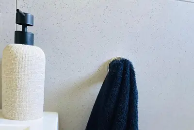 a bottle of soap and a towel on a wall at The Minimalist Hideout in Erand