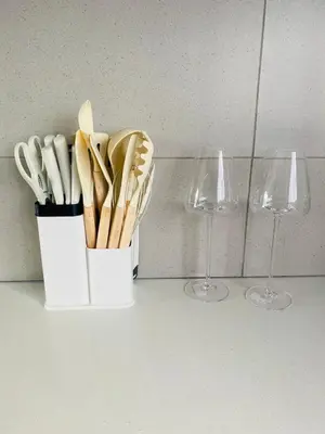 a white cup with utensils and two wine glasses at The Minimalist Hideout in Erand