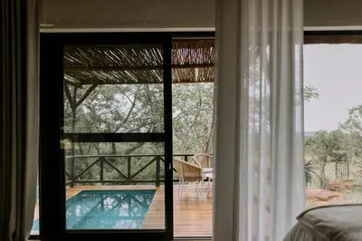 a room with a view of a swimming pool through a window at Rhino Plains in Welgevonden Game Reserve