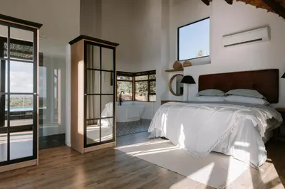 a bedroom with a bed and a tub and a mirror at Rhino Plains in Welgevonden Game Reserve