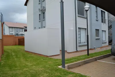 a white building with a light pole in the grass at Moon Octave in Midrand