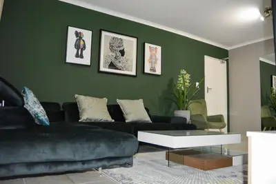 a living room with green walls and a black couch at Moon Octave in Midrand