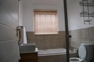 a bathroom with a sink and a toilet and a window at Moon Octave in Midrand