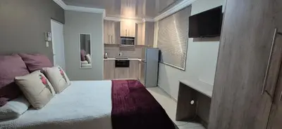 a small room with a bed and a kitchen at Ekuhlaleni - A home away from home R8 in Pretoria
