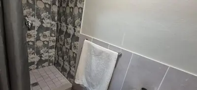 a bathroom with a white towel hanging on a wall at Ekuhlaleni - A home away from home R8 in Pretoria