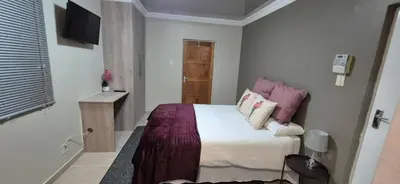 a small bedroom with a bed and a television at Ekuhlaleni - A home away from home R8 in Pretoria