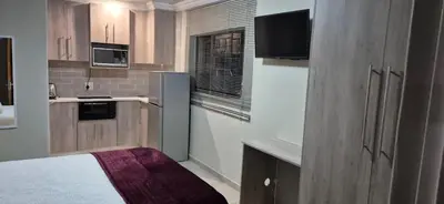 a small kitchen with a refrigerator and a window at Ekuhlaleni - A home away from home R8 in Pretoria