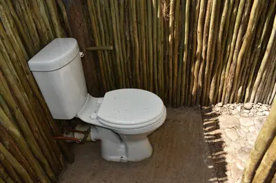a toilet sitting in a corner of a wooden wall at Bush Babies Camp in Cambridge