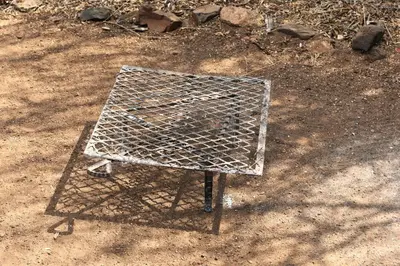 a metal grill on the ground in the dirt at Bush Babies Camp in Cambridge