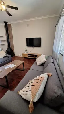 a living room with a gray couch and a flat screen tv at 21 on Main in Benoni