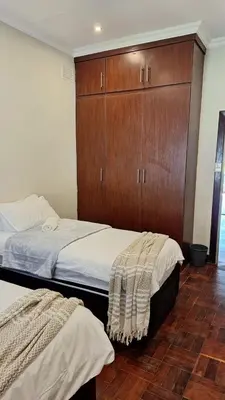 a bedroom with two beds and a wooden cabinet at 21 on Main in Benoni