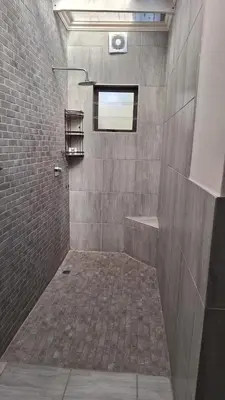 a bathroom with a shower with a brick wall at 21 on Main in Benoni