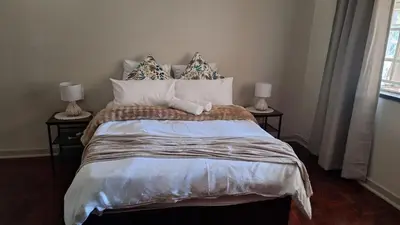 a bedroom with a large bed with two side tables at 21 on Main in Benoni