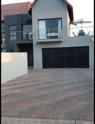 a house with a black garage door and a brick driveway at Mountain view in Hartbeespoort