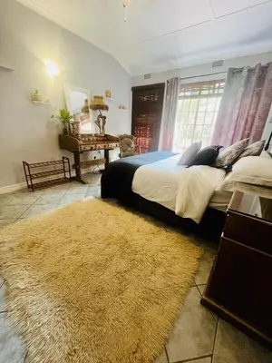 a bedroom with a large bed and a rug at Follyfoot Manor in Midrand