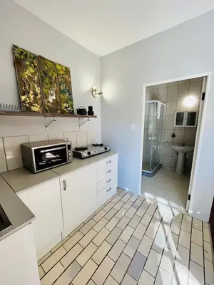 a kitchen with a microwave on a counter and a bathroom at Follyfoot Manor in Midrand