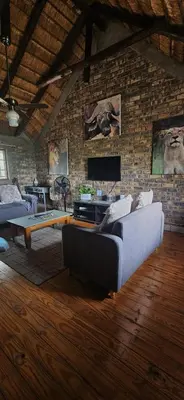 a living room with a couch and a brick wall at Cottage On Naboom in Marloth Park