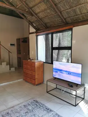 a living room with a flat screen tv on a table at The Thatched Cottage in Benoni