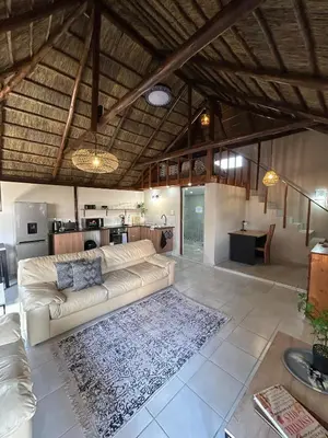a living room with a couch and a kitchen at The Thatched Cottage in Benoni