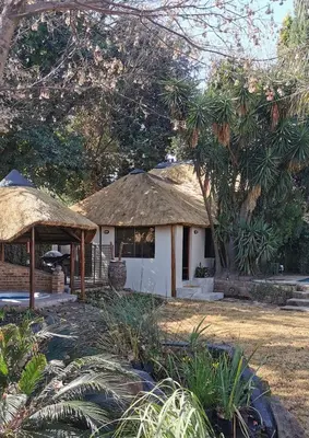 a small white building with a thatched roof at The Thatched Cottage in Benoni