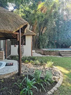 a resort with a thatched roof and a garden at The Thatched Cottage in Benoni