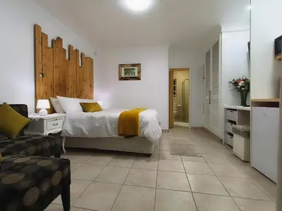 a bedroom with a bed and a living room at Wag-n-Bietjie in Centurion