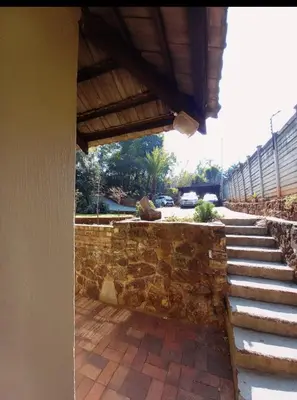 a house with a stone wall and stairs at Wag-n-Bietjie in Centurion