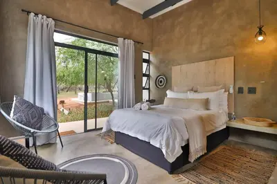 a bedroom with a large bed and a large window at Maroela Skadu in Marloth Park in Marloth Park
