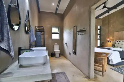 a bathroom with a sink and a toilet and a bed at Maroela Skadu in Marloth Park in Marloth Park