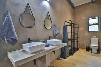 a bathroom with two sinks and mirrors on the wall at Maroela Skadu in Marloth Park in Marloth Park