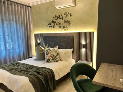 a hotel room with a bed and a green chair at The Cycad Lodge & Chalets in Nelspruit