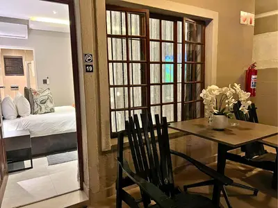a dining room with a table and a bedroom at The Cycad Lodge & Chalets in Nelspruit