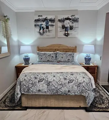 a bedroom with a bed with two lamps and pictures on the wall at Upstairs R-4 Self Catering Unit in White River