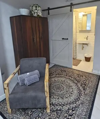 a living room with a chair and a bathroom at Upstairs R-4 Self Catering Unit in White River