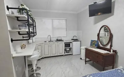 a white kitchen with a sink and a mirror at Upstairs R-4 Self Catering Unit in White River