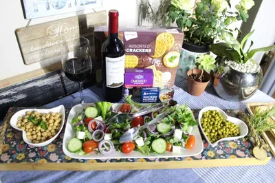 a table with a plate of food and a bottle of wine at Rose Stable Cottage in Pretoria