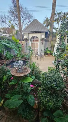 a garden with a deck with a gate and flowers at Rose Stable Cottage in Pretoria