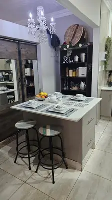 a kitchen with a island with two stools in it at Rose Stable Cottage in Pretoria