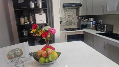 a kitchen with a bowl of fruit and a vase of flowers at Rose Stable Cottage in Pretoria