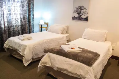 two beds in a room with white sheets and towels at Premier Hotel and Spa Cullinan in Cullinan