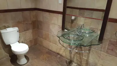 a bathroom with a toilet and a glass sink at Premier Hotel and Spa Cullinan in Cullinan
