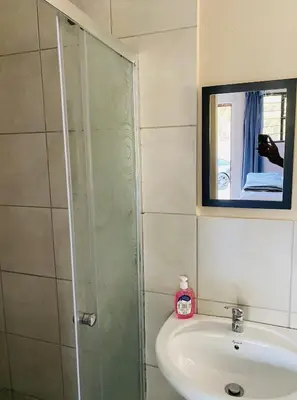 a bathroom with a sink and a shower with a mirror at Lesari Stay in Centurion