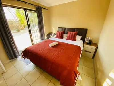 a bedroom with a large bed with a red blanket at Lesari Stay in Centurion