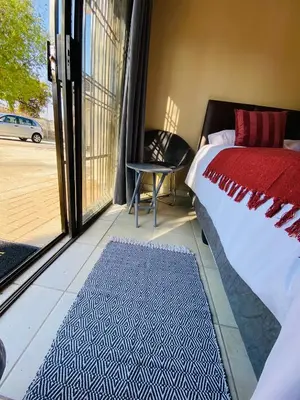 a bedroom with a bed and a chair and a window at Lesari Stay in Centurion