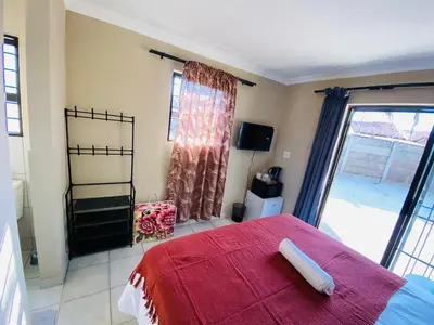 a bedroom with a red bed and a large window at Lesari Stay in Centurion