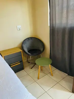 a bedroom with a black chair and a green stool at Lesari Stay in Centurion