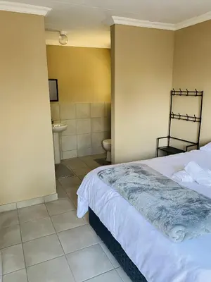 a bedroom with a bed and a bathroom with a toilet at Lesari Stay in Centurion