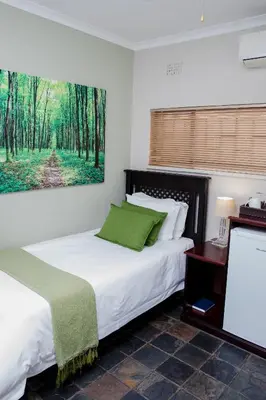 a bedroom with two beds and a painting on the wall at 85 Ehmke Guesthouse in Nelspruit