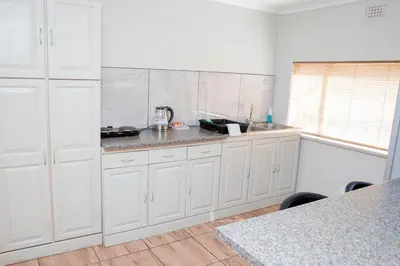 a kitchen with white cabinets and a counter top at 85 Ehmke Guesthouse in Nelspruit
