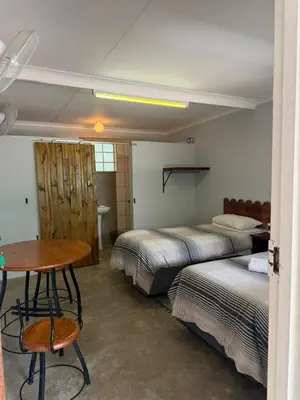 a bedroom with two beds and a table and a desk at Kanaan Guest Farm in Hazyview